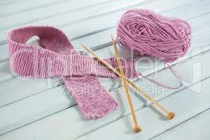 High angle view of pink woolen Breast Cancer Awareness ribbon with crochet needles on table