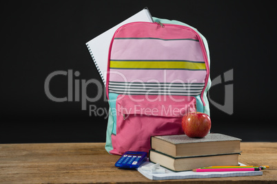 Apple on stack of books with calculator and school bag