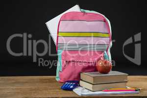 Apple on stack of books with calculator and school bag