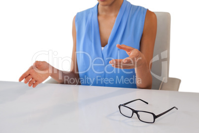 Mid section of businesswoman gesturing while sitting at table