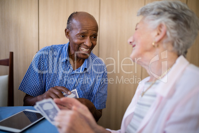 Smiling senior male and female friends playing cards