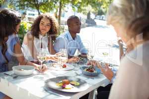 Happy friends interacting with each other while having meal