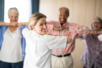 Rear view of smiling female doctor exercising with senior people Rear view of smiling female doctor exercising with senior people