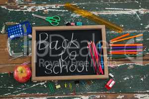 Back to school text written on chalkboard with various stationery and apple
