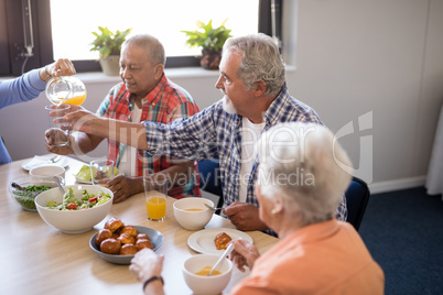 Cropped image of woman serving juice to friends