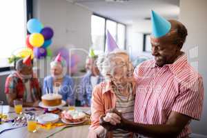 Happy senior couple wearing party hats with friends