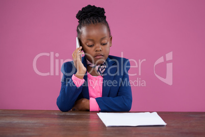 Concentrated businesswoman using mobile phone at desk
