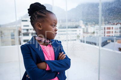 Thoughtful businesswoman with arms crossed standing by window