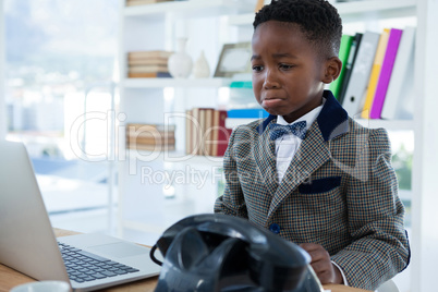 Sad businessman making face while looking at laptop