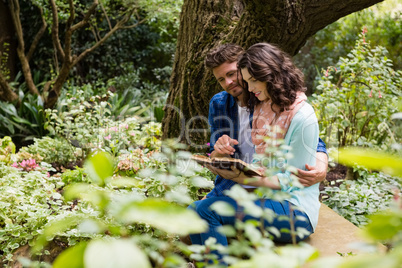 Romantic couple reading book on bench in garden