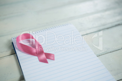 High angle view of pink Breast Cancer Awareness ribbon and spiral notepad