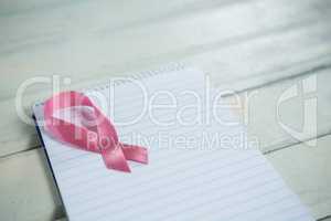 High angle view of pink Breast Cancer Awareness ribbon and spiral notepad