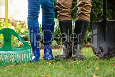 Couple standing with gardening rake and shovel in garden