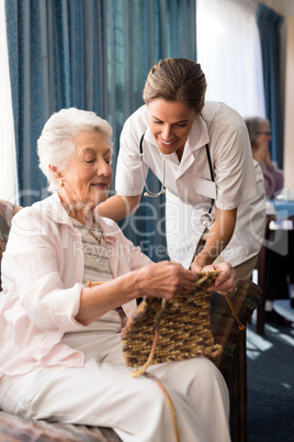 Senior woman showing knitting to female doctor