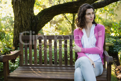 Smiling beautiful woman sitting on bench in park