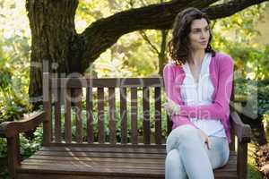 Smiling beautiful woman sitting on bench in park