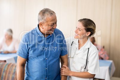 Smiling senior man looking at young female doctor