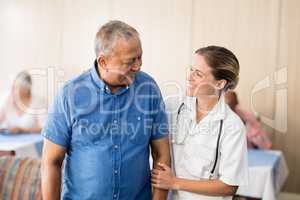 Smiling senior man looking at young female doctor