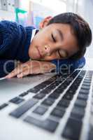 Close up of boy imitating as businessman sleeping on laptop