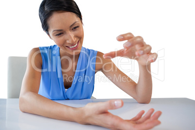 Smiling young businesswoman gesturing while holding something at table