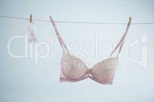 Pink Breast Cancer Awareness ribbon hanging by bra on string