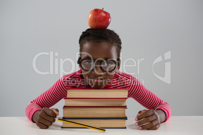 Schoolgirl leaning on books stack against white background