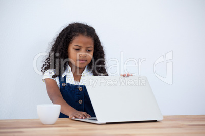 Businesswoman holding laptop by coffee cup at table