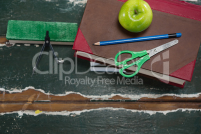 Various stationery with books and apple on wooden table