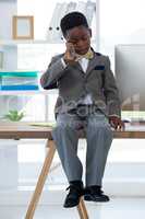 Businessman talking on smartphone while sitting on desk