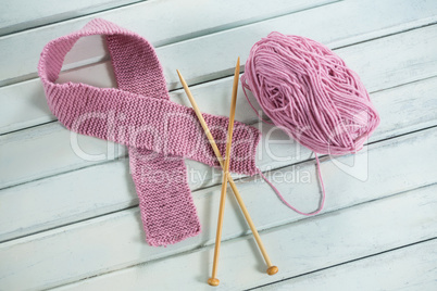High angle view of pink woolen Breast Cancer Awareness ribbon with crochet needles