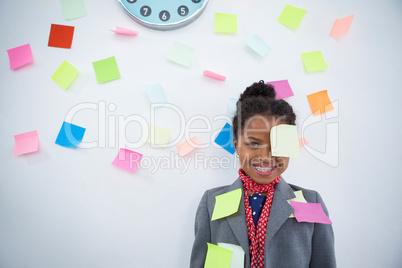 Smiling businesswoman with sticky notes stuck on suit and head