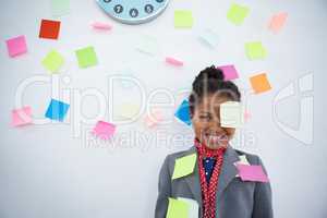 Smiling businesswoman with sticky notes stuck on suit and head