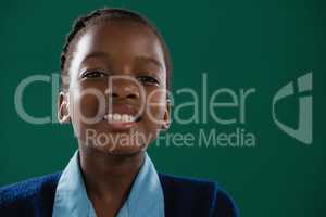 Smiling schoolgirl standing against green background