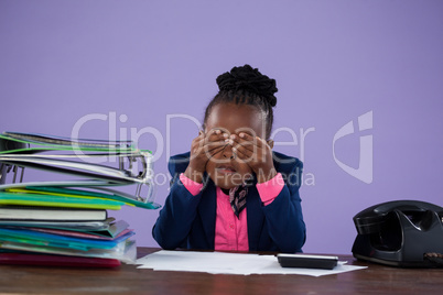 Tired businesswoman covering eyes at desk