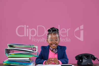 Portrait of smiling businesswoman with files and telephone at desk