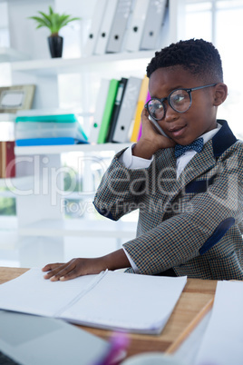 Businessman using mobile phone and reading book at desk