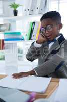 Businessman using mobile phone and reading book at desk