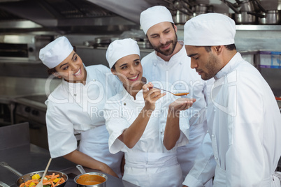 Chef tasting food to colleague in kitchen