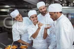 Chef tasting food to colleague in kitchen