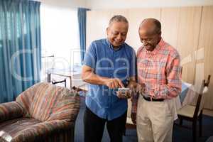 Smiling senior male friends using mobile phone