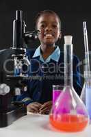 Schoolgirl using microscope against black background
