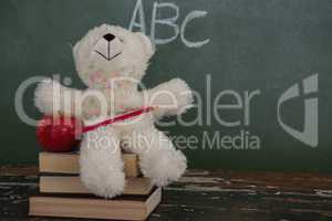 Teddy bear, pencil and apple on stack of books