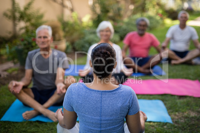 Trainer guiding senior people in meditating exercise