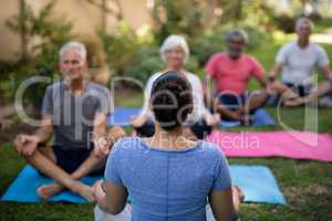 Trainer guiding senior people in meditating exercise