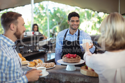 Waiter serving coffee to customer at counter