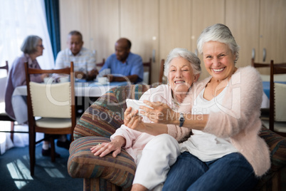 Portrait of smiling senior woman taking selfie with friend