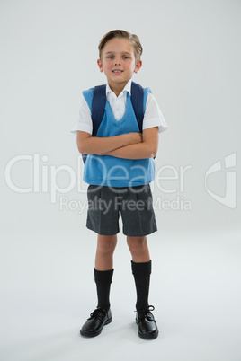 Portrait of cute schoolboy standing with arms crossed