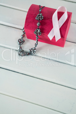 High angle view of pink Breast Cancer Awareness ribbon and jewelry with red box