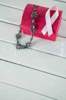 High angle view of pink Breast Cancer Awareness ribbon and jewelry with red box