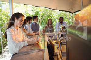 Smiling woman using mobile phone while having a glass of champagne